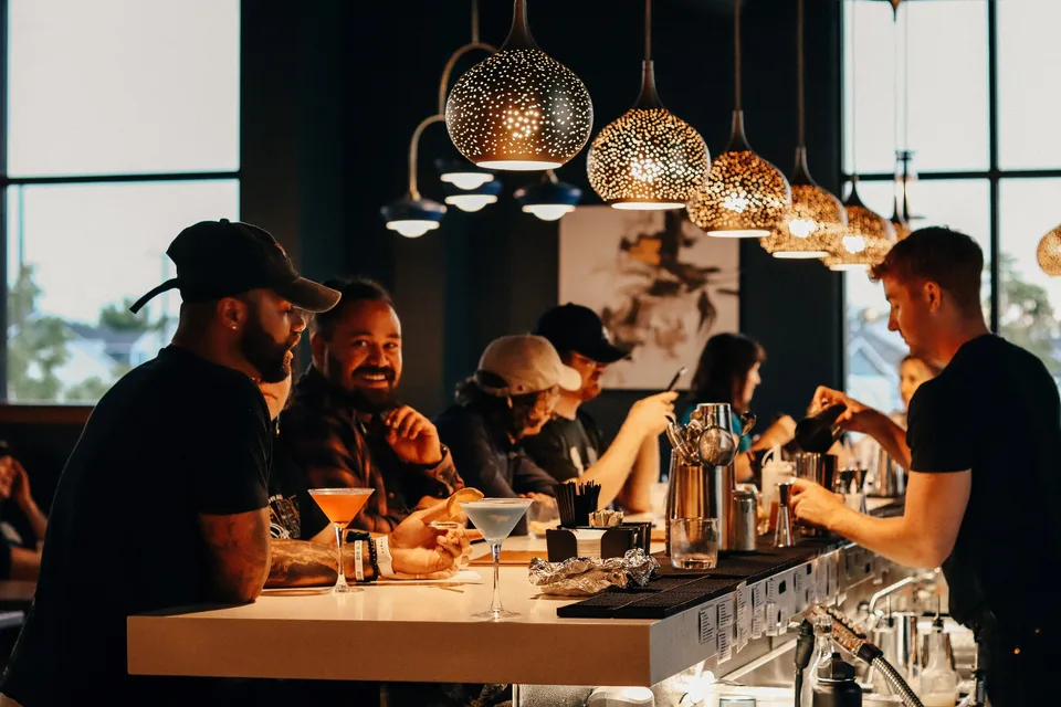 Guests enjoying cocktails across the bar from a bartender at After Hours.