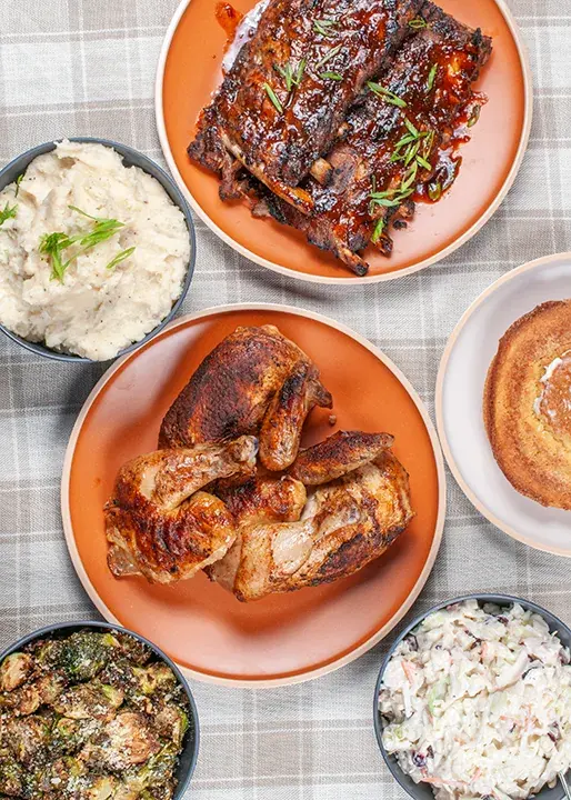 Roasted chicken and glazed ribs with mashed potatoes, slaw, and side dishes.