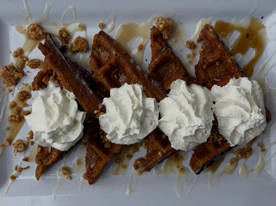 Waffle quarters topped with whipped cream and a drizzle at Oak and Maple.
