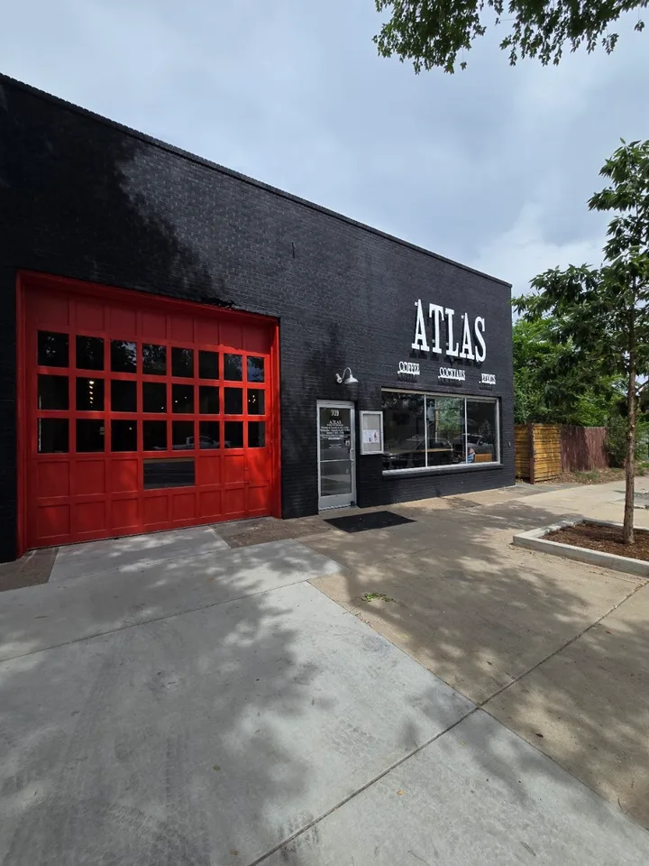 The Atlas café exterior with black brick, a red garage door, and white Atlas lettering above the front window.