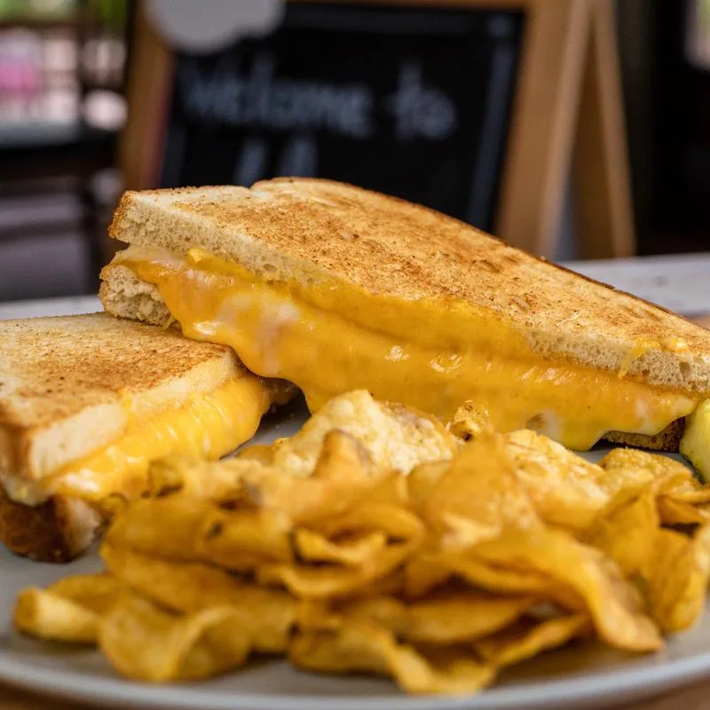 A grilled cheese sandwich with melted cheese and potato chips at The Cow.