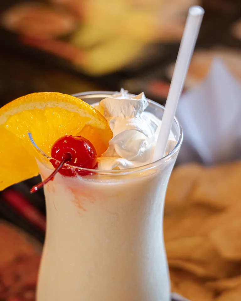 A creamy drink topped with whipped cream, an orange slice and a cherry at Tres Amigos.